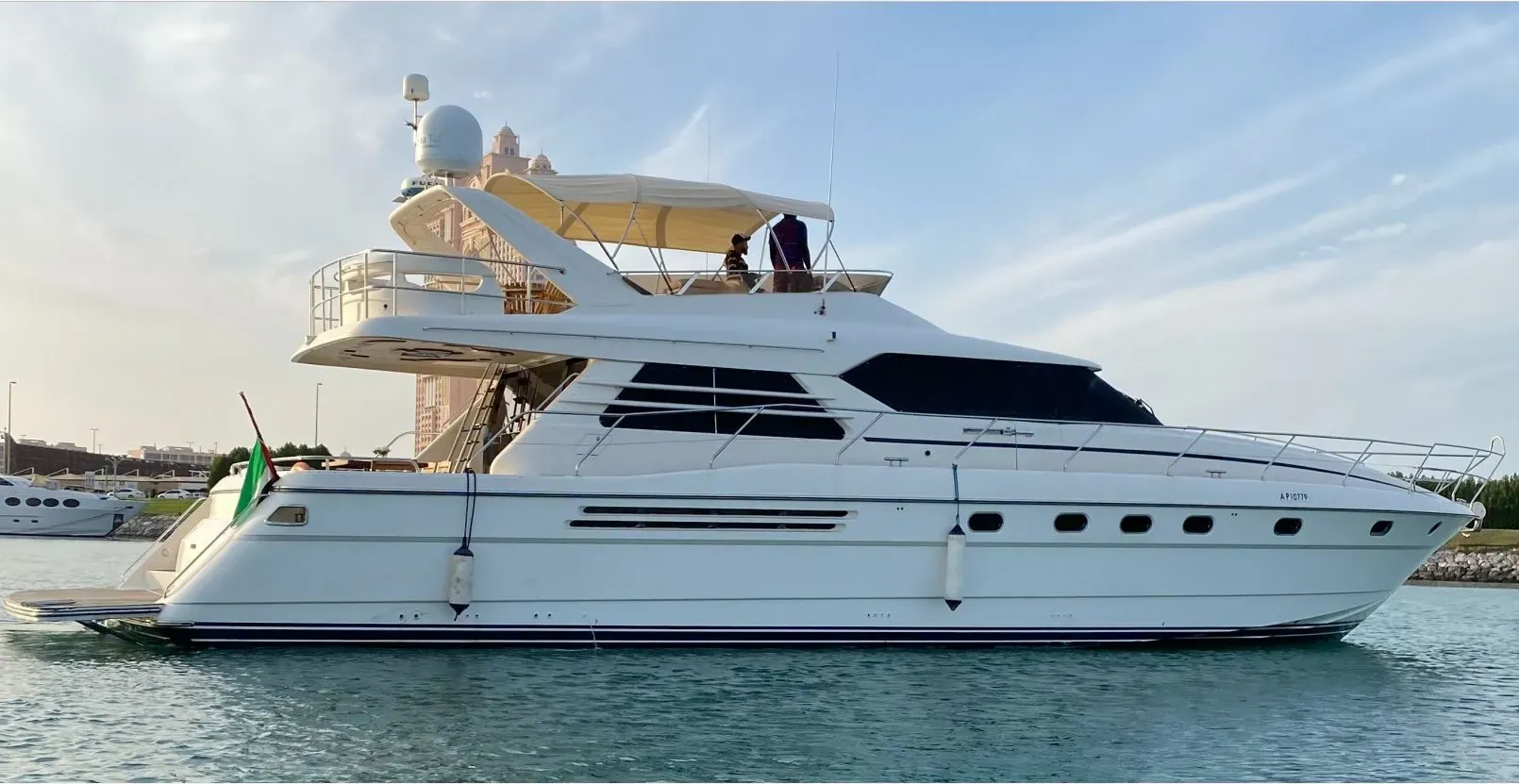 White motor yacht with a flybridge at anchor in calm Abu Dhabi water